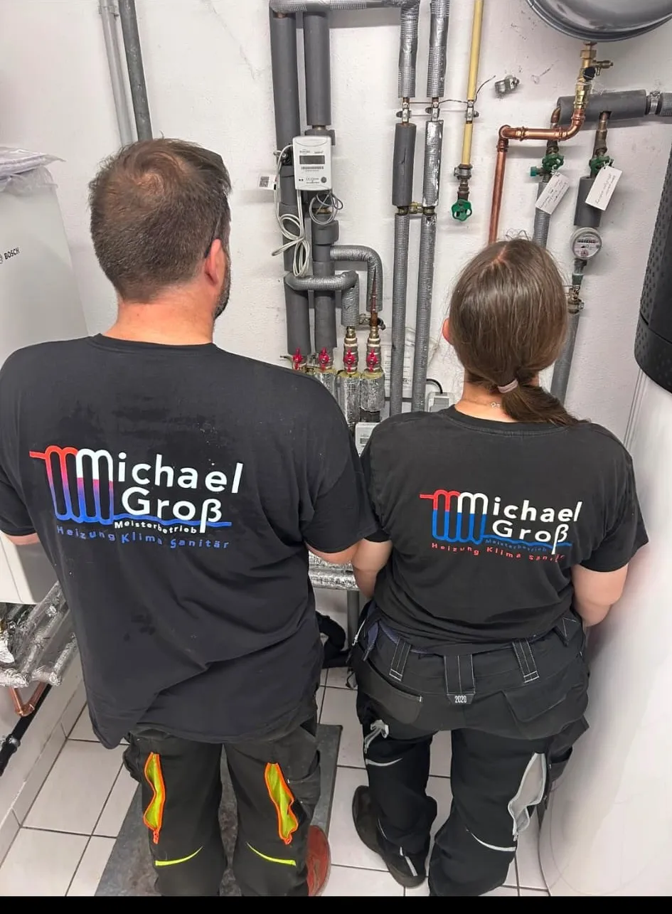 Michael Groß und Kollegin im Firmenshirt vor einer Heizungsanlage